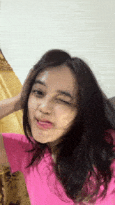 a woman in a pink shirt is making a silly face