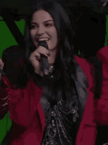 a woman is smiling while holding a microphone .