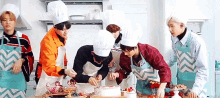 a group of people wearing chef hats and aprons are cutting a cake .