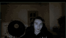 a man wearing headphones is sitting in front of a dart board in a dark room
