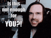 a man with long hair is making a funny face and says " is this not enough for you "