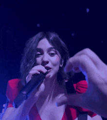 a woman singing into a microphone with a blue background