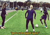a group of women are playing soccer on a field and one of them says " gets nutmegged again "