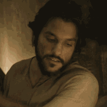 a man with a beard wearing a tan shirt