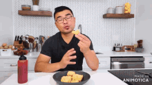 a man in a black shirt is eating chicken nuggets from a black bowl