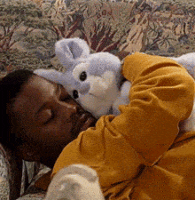 a man laying on a couch holding a stuffed bunny rabbit