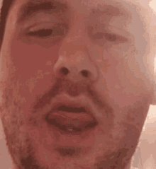 a man with a beard is sticking his tongue out in a close up of his face .