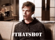 a man is sitting on a couch with blood coming out of his mouth and the words that shot written on the bottom .