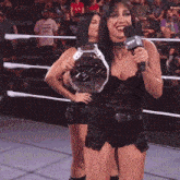 two women in a wrestling ring one holding a trophy and the other holding a microphone that says nxt on it