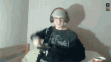 a man wearing headphones and glasses is sitting on a bed with a can of soda .
