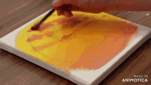 a person is painting a yellow and orange circle on a canvas that is made in animatica