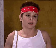 a woman wearing a white tank top and a red headband