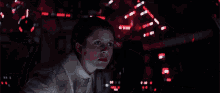 a woman with a surprised look on her face is sitting in a dark room with red lights behind her