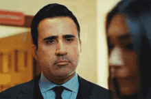 a man in a suit and tie is looking at a woman in a room