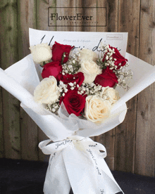 a bouquet of red and white roses with baby 's breath wrapped in white paper from flowerever