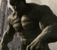 a close up of a hulk without a shirt standing in front of a castle .