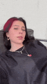 a woman with red hair and black hair is wearing a black shirt and a necklace .