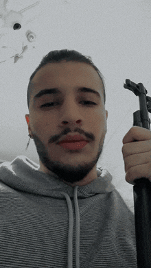 a man with a beard is holding a gun in his right hand