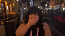 a woman covering her mouth with her hand in front of a blurry background that says shigarita