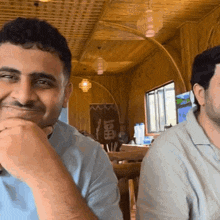 two men are sitting at a table in front of a sign that says ' i love you ' on it