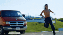 a man without a shirt is running towards a dodge van
