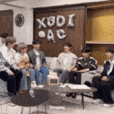 a group of people are sitting on a couch in a living room with balloons that say xodi ac .