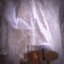 a person standing in a waterfall with a white cloth hanging from the ceiling
