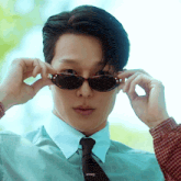 a man wearing sunglasses and a plaid shirt has the name anneji on the bottom of his shirt