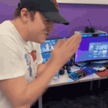 a man wearing a black hat is clapping in front of a computer screen