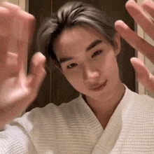 a young man in a white robe is making a hand gesture .