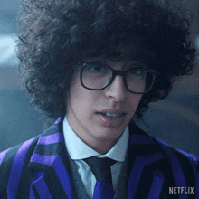 a man with curly hair is wearing glasses and a purple suit with netflix on the bottom