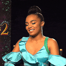 a woman in a blue dress is smiling in front of a sign with the number 2