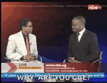 two men are sitting in front of a sign that says why are you gae ?