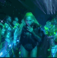 a woman in a black bodysuit stands in front of a crowd of people