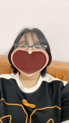 a girl wearing glasses and a shirt with a smiley face on it makes a funny face
