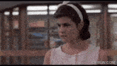 a woman in a white dress is standing in front of a window with gifrun.com written on the bottom of the screen