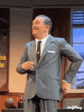 a man in a suit and tie is standing with his hands on his hips and the word imgplay is on the bottom right