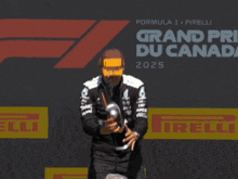 a man holding a trophy in front of a sign that says grand prix du canada 2025