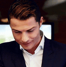 a man in a suit and white shirt is looking down at something