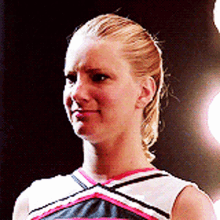 a cheerleader with blonde hair is wearing a black and white top