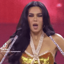 a woman with long black hair is standing on a stage with her tongue out and a necklace around her neck .