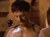 a shirtless man with a towel around his neck is looking down