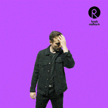 a man in a black jacket stands in front of a purple background