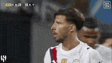 a soccer player in a white shirt stands in front of a scoreboard that says da zn