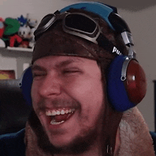a man wearing a helmet and headphones is laughing with his eyes closed