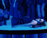 a woman is laying on the floor in front of a crowd of people