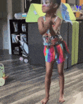a little girl with face paint on her face is standing on a wood floor