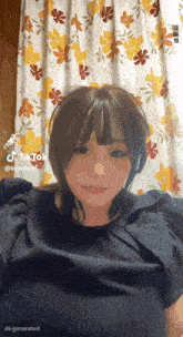 a woman is standing in front of a floral curtain with tiktok written on the bottom right