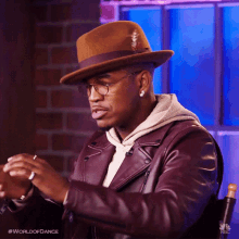 a man wearing a hat and glasses is sitting in a chair with the words world of dance written on the bottom