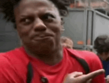 a man in a red shirt is making a funny face while looking at his phone .